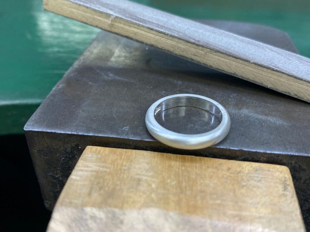 指輪の腕を紙ヤスリで甲丸に形を整えているところ